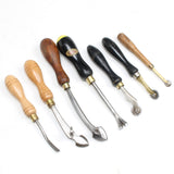 Set of leatherworking tools with wooden handles on a white background